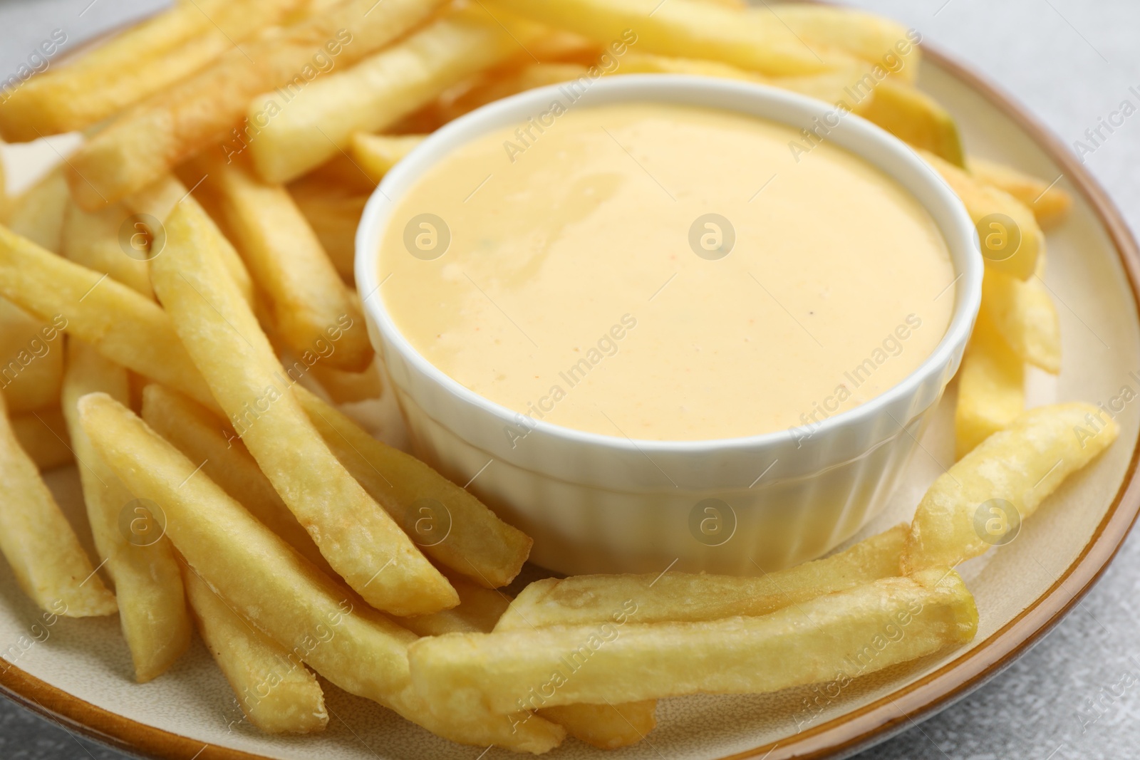 Tasty cheese sauce in bowl and French fries on table, closeup Photo of Tasty cheese sauce in bowl and French fries on table, closeup