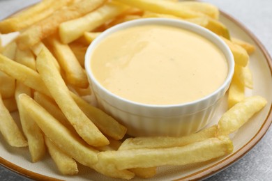 Photo of Tasty cheese sauce in bowl and French fries on table, closeup
