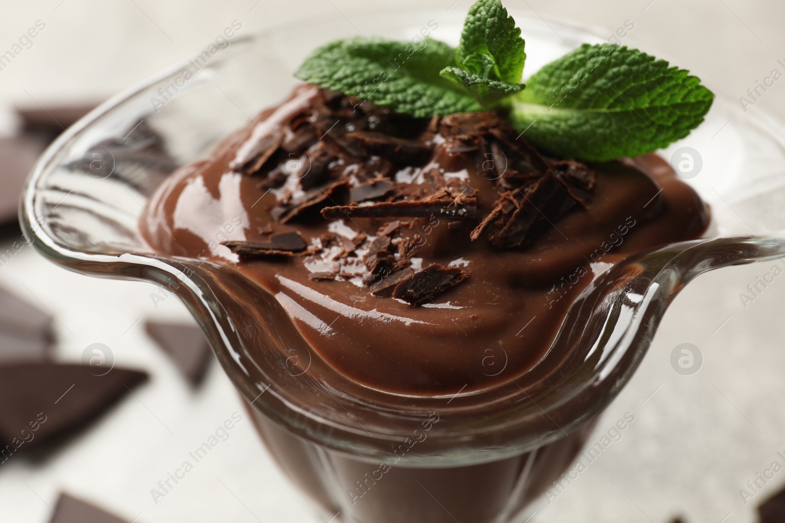 Photo of Delicious chocolate mousse in glass dessert bowl on grey table, closeup