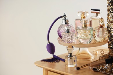 Photo of Different luxury perfumes on wooden dressing table indoors, space for text