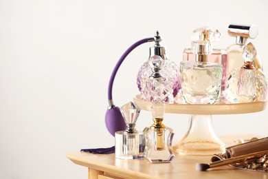 Photo of Different luxury perfumes on wooden dressing table indoors, space for text