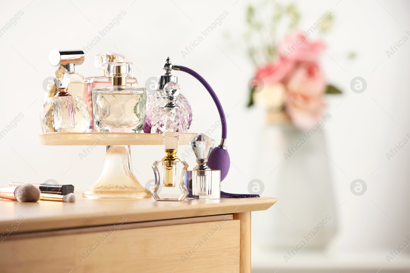 Different luxury perfumes on wooden dressing table indoors, space for text Photo of Different luxury perfumes on wooden dressing table indoors, space for text