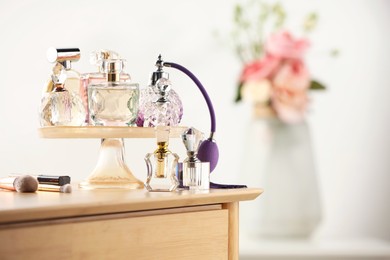 Photo of Different luxury perfumes on wooden dressing table indoors, space for text