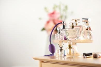 Photo of Different luxury perfumes on wooden dressing table indoors, space for text