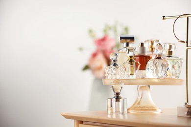 Photo of Different luxury perfumes on wooden dressing table indoors, space for text