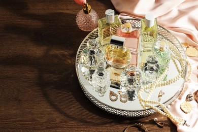 Photo of Different luxury perfumes and accessories on wooden table, space for text
