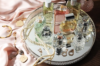 Photo of Different luxury perfumes and accessories on wooden table