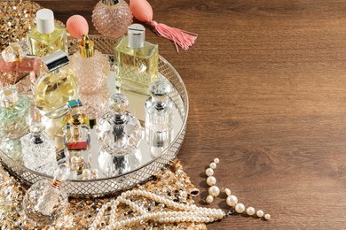Photo of Different luxury perfumes and accessories on wooden table, space for text