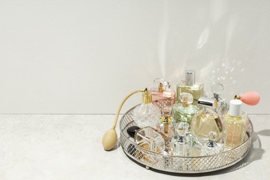 Photo of Different luxury perfumes and accessories on light textured table, space for text