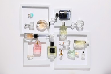 Photo of Different luxury perfumes on white background, flat lay
