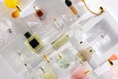 Photo of Different luxury perfumes on white background, flat lay