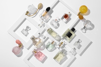 Photo of Different luxury perfumes on white background, flat lay