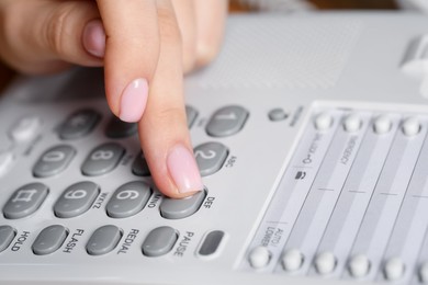 Photo of Woman dialing number on landline telephone, closeup