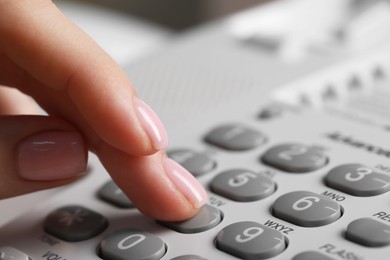 Photo of Woman dialing number on landline telephone, closeup