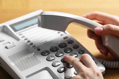 Photo of Woman dialing number on telephone at table, closeup