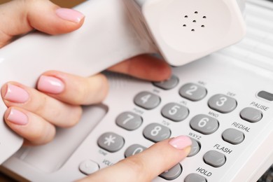 Photo of Woman dialing number on landline telephone, closeup