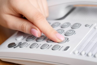 Photo of Woman dialing number on landline telephone, closeup