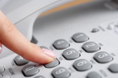 Photo of Woman dialing number on landline telephone, closeup