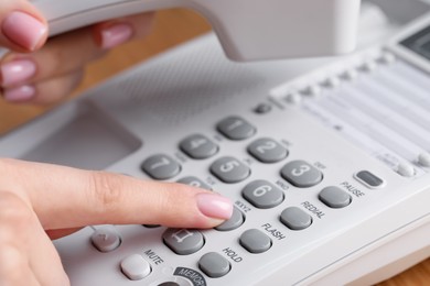 Photo of Woman dialing number on telephone at table, closeup