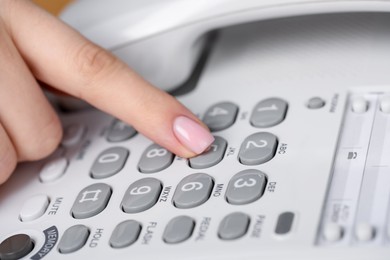 Photo of Woman dialing number on landline telephone, closeup