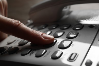 Photo of Woman dialing number on landline telephone, closeup