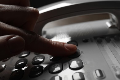 Photo of Woman dialing number on landline telephone, closeup