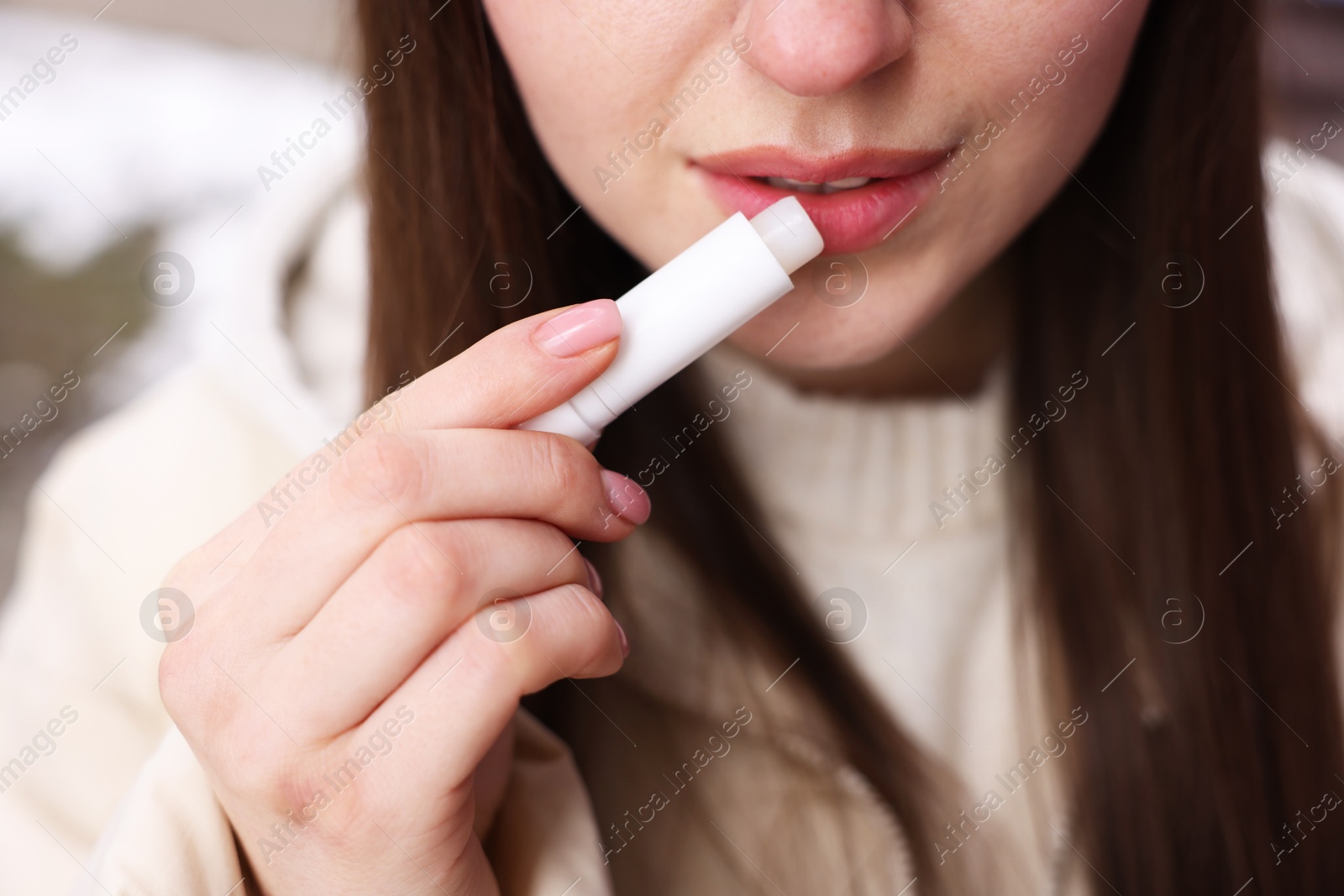 Photo of Young woman applying lip balm outdoors, closeup