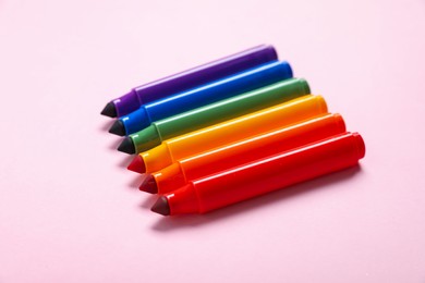 Photo of Many colorful markers on pink background, closeup