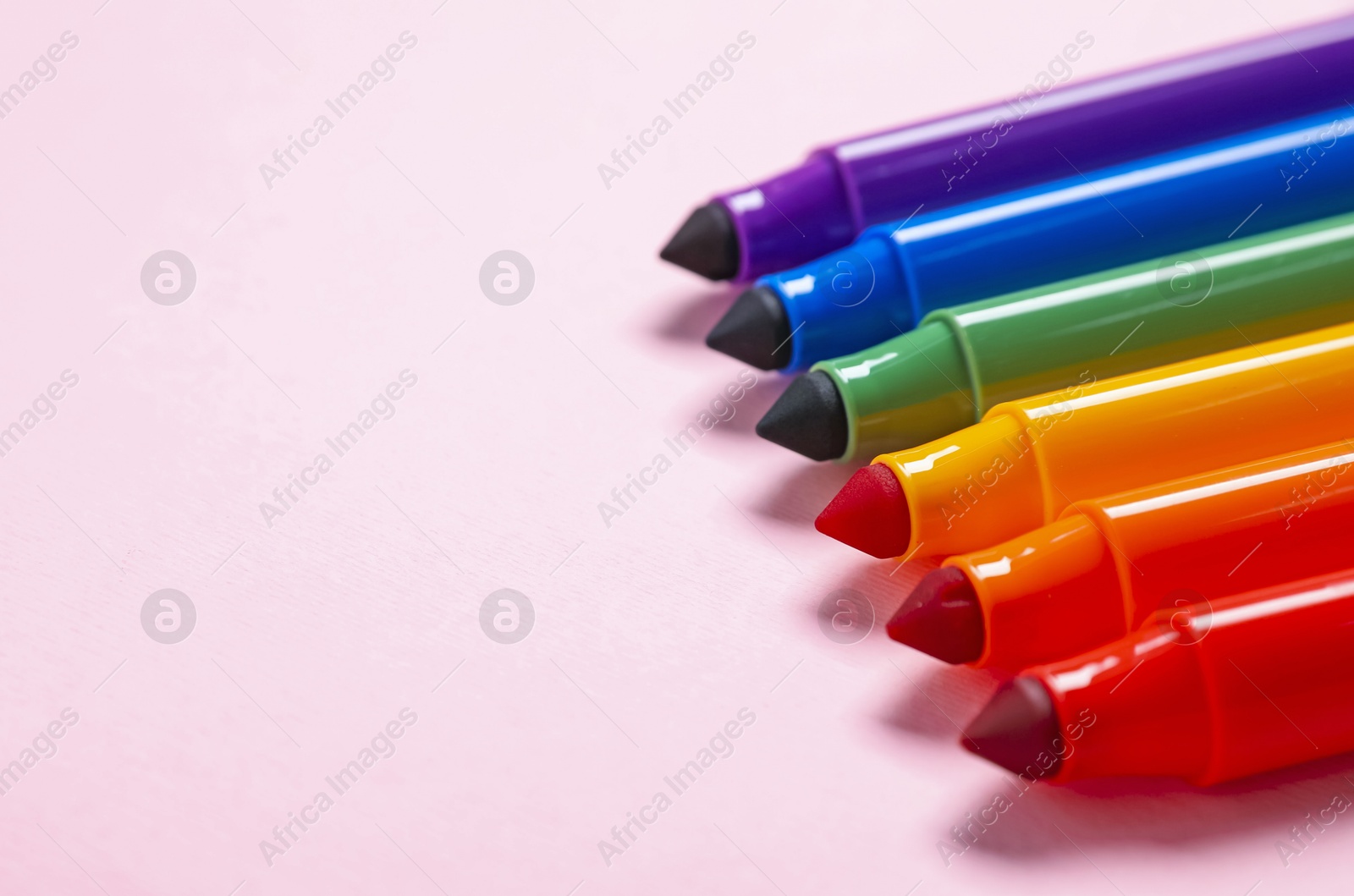 Photo of Many colorful markers on pink background, closeup. Space for text