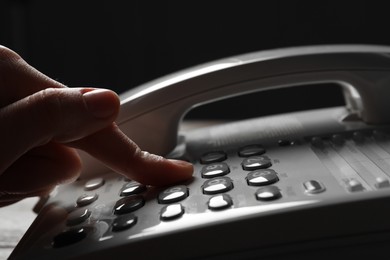 Photo of Woman dialing number on landline telephone, closeup