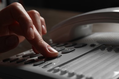 Photo of Woman dialing number on landline telephone at table, closeup