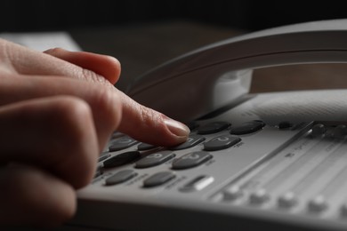 Photo of Woman dialing number on landline telephone, closeup