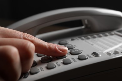 Photo of Woman dialing number on landline telephone, closeup