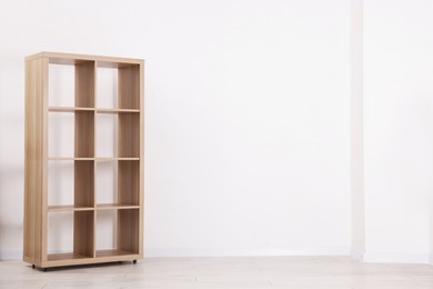 Photo of Empty wooden shelving unit near white wall indoors, space for text