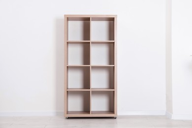 Photo of Empty wooden shelving unit near white wall indoors