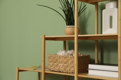 Photo of Wooden shelving unit with different home decor near olive wall indoors, closeup