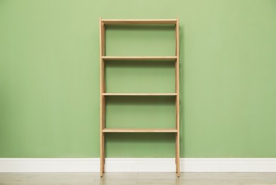 Photo of Empty wooden shelving unit near olive wall indoors