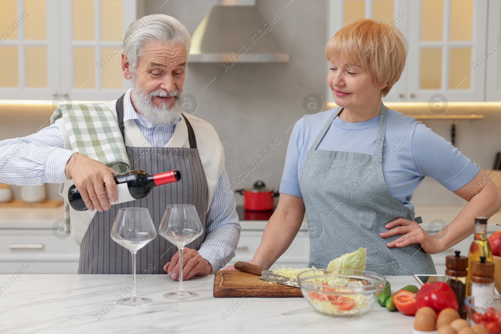 Photo of Senior couple having wine while cooking in kitchen