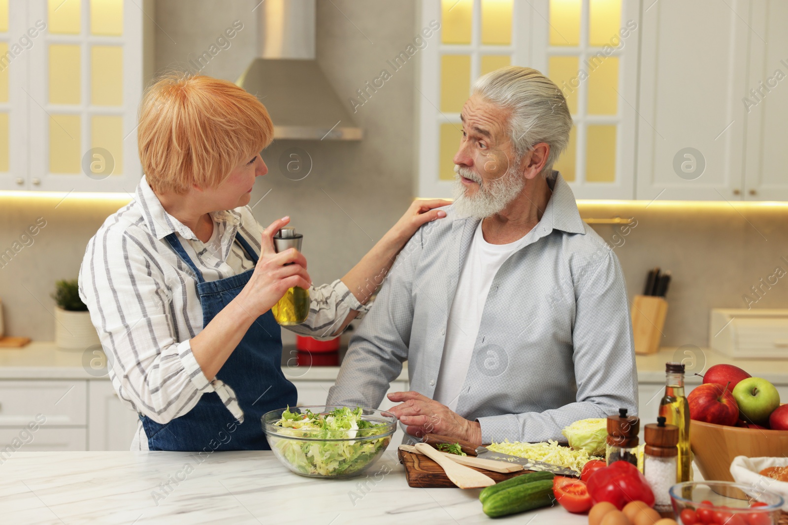 Photo of Senior couple cooking together at table in kitchen