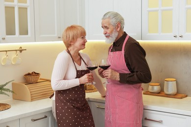 Senior couple with glasses of wine in kitchen