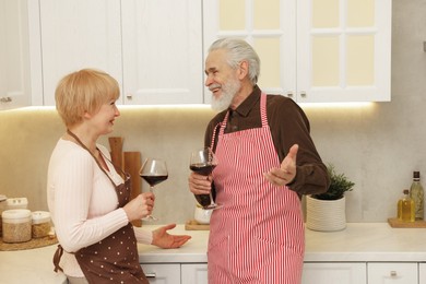 Senior couple with glasses of wine in kitchen