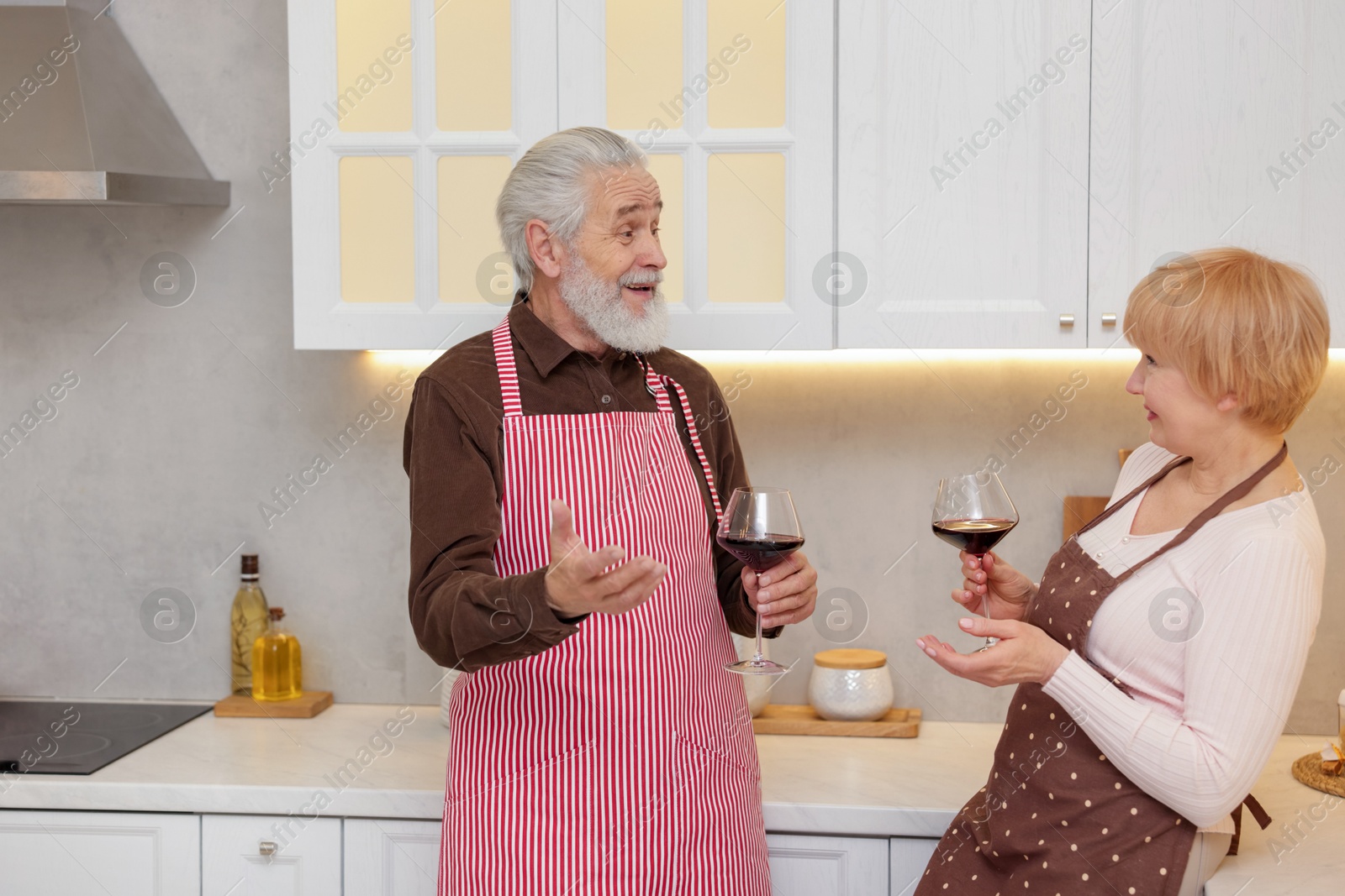 Photo of Senior couple with glasses of wine in kitchen