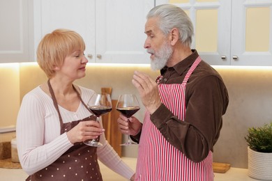 Photo of Senior couple with glasses of wine in kitchen