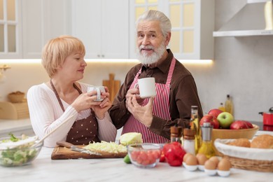 Photo of Senior couple having tea while cooking together in kitchen