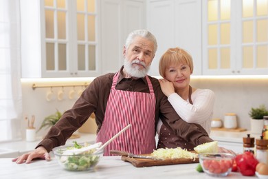 Photo of Senior couple cooking together at table in kitchen