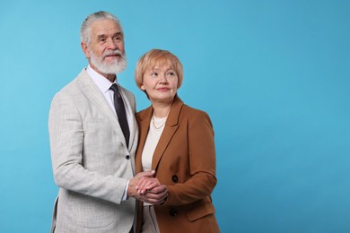 Photo of Lovely senior couple holding hands on light blue background. Space for text