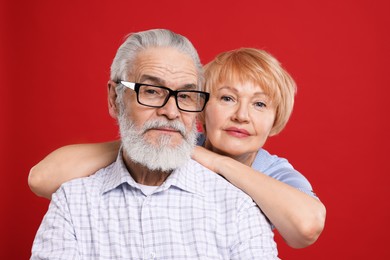 Portrait of lovely senior couple on red background