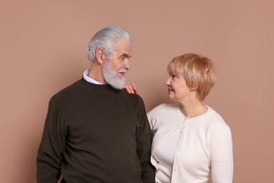 Photo of Lovely senior couple looking at each other on beige background