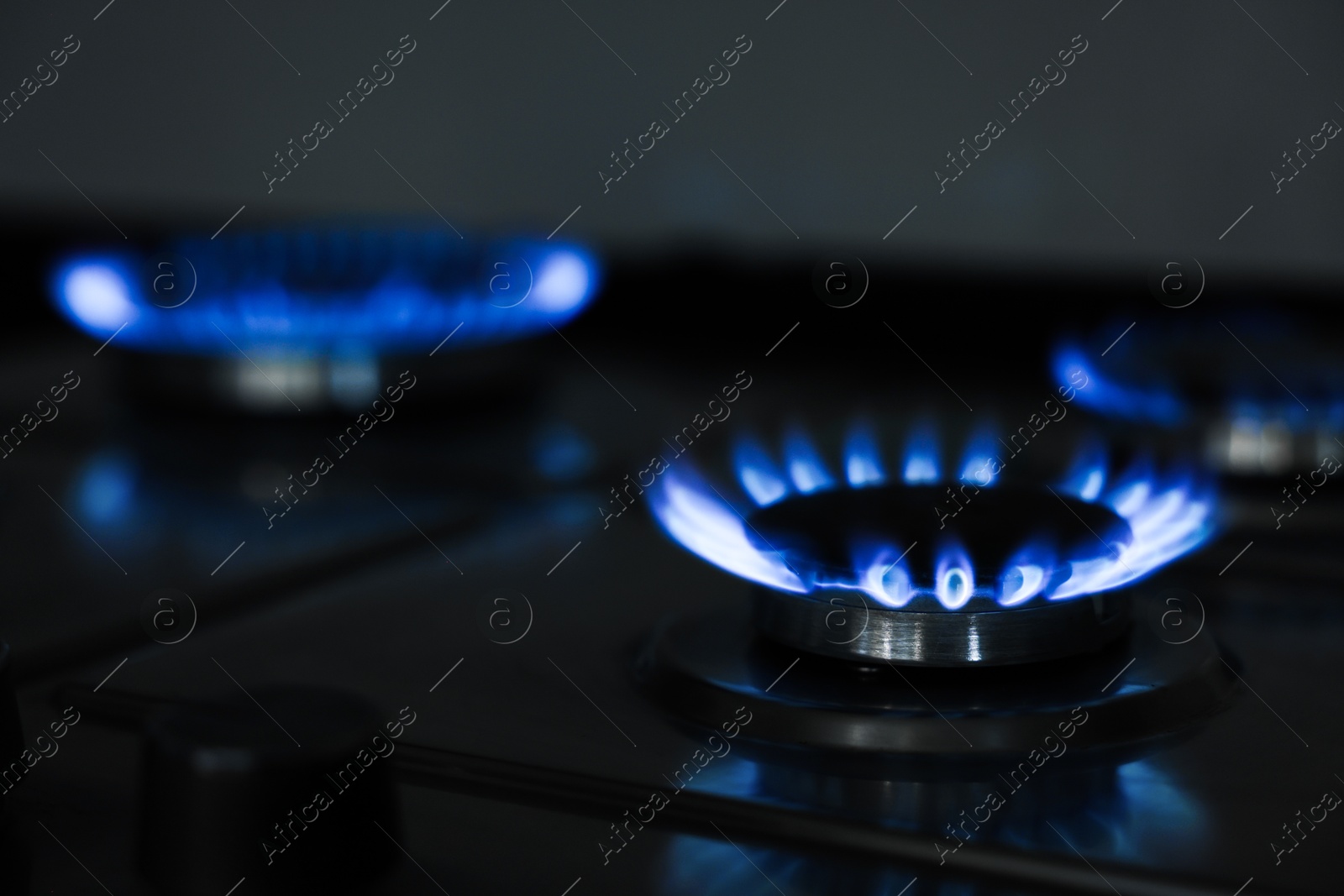 Photo of Gas burners with blue flame on stove, closeup