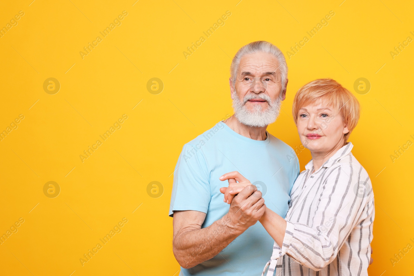 Photo of Lovely senior couple holding hands on orange background. Space for text